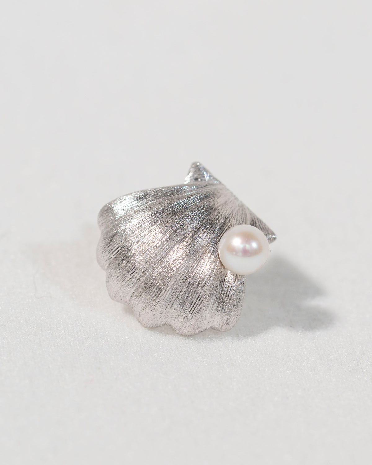 Angled view of a sterling silver shell stud earring with freshwater pearl showing its sculptural form
