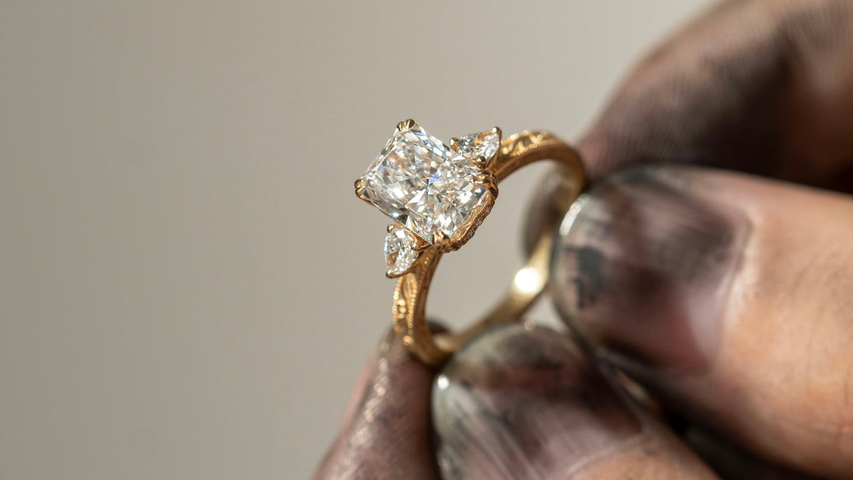 A custom three-stone ring held at the jeweler's bench.