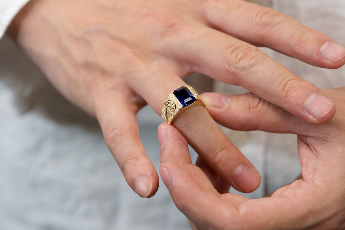 A custom wide-band ring with a deep-blue rectangular center stone worn on a hand.