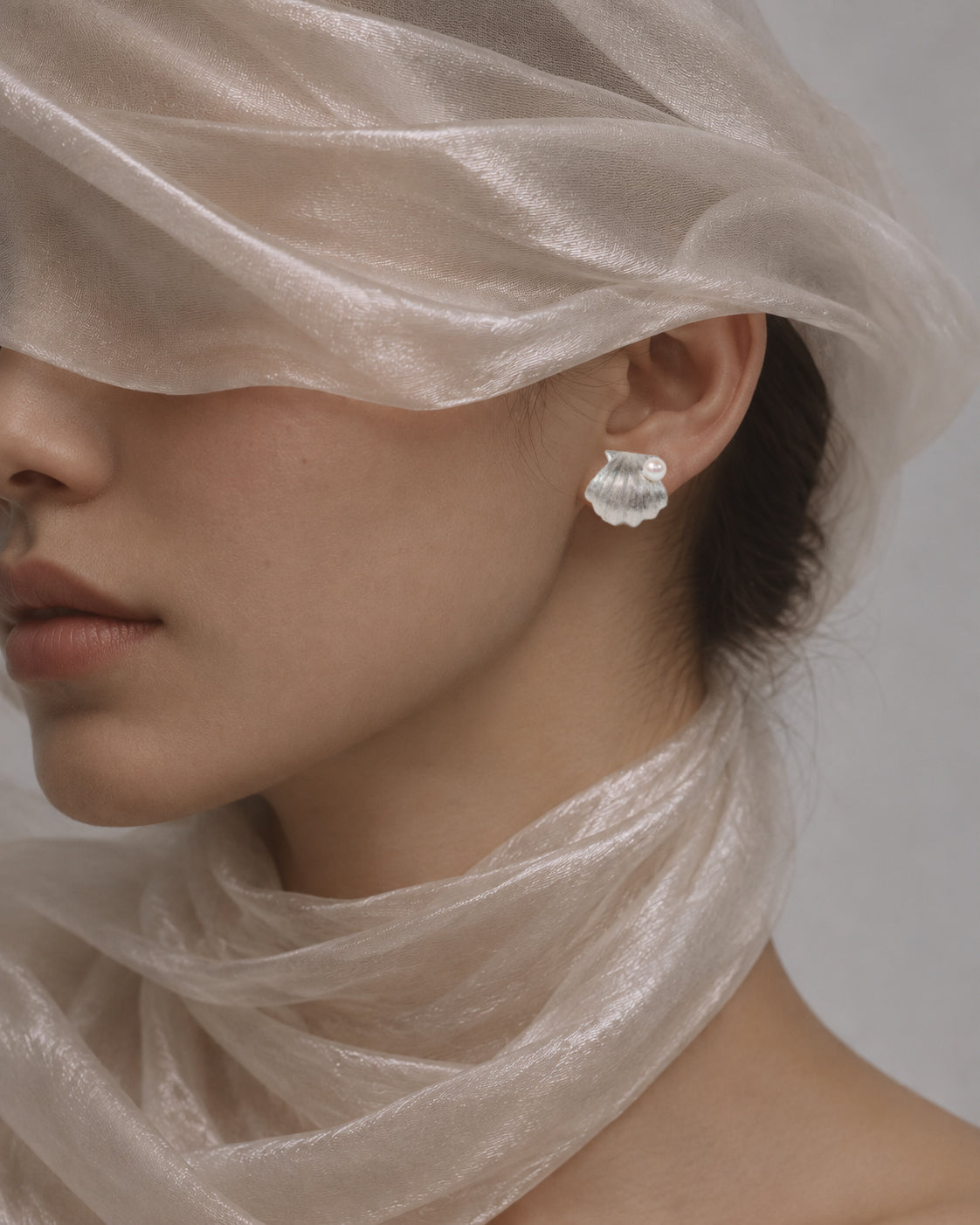 Editorial portrait featuring a silver shell stud earring with a pearl.