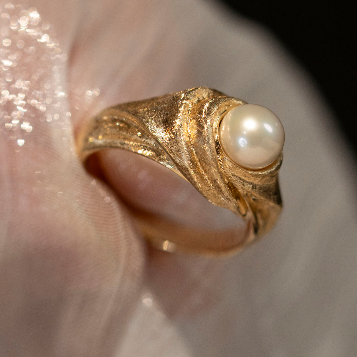 Full view of the Silk in Gold 18K gold freshwater pearl ring on sheer fabric, showing the hand-worked gold folds and complete ring shape.