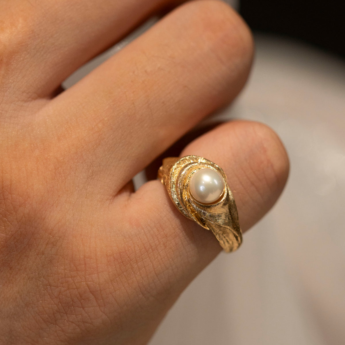 The Silk in Gold 18K gold freshwater pearl ring worn on a hand to show its scale.
