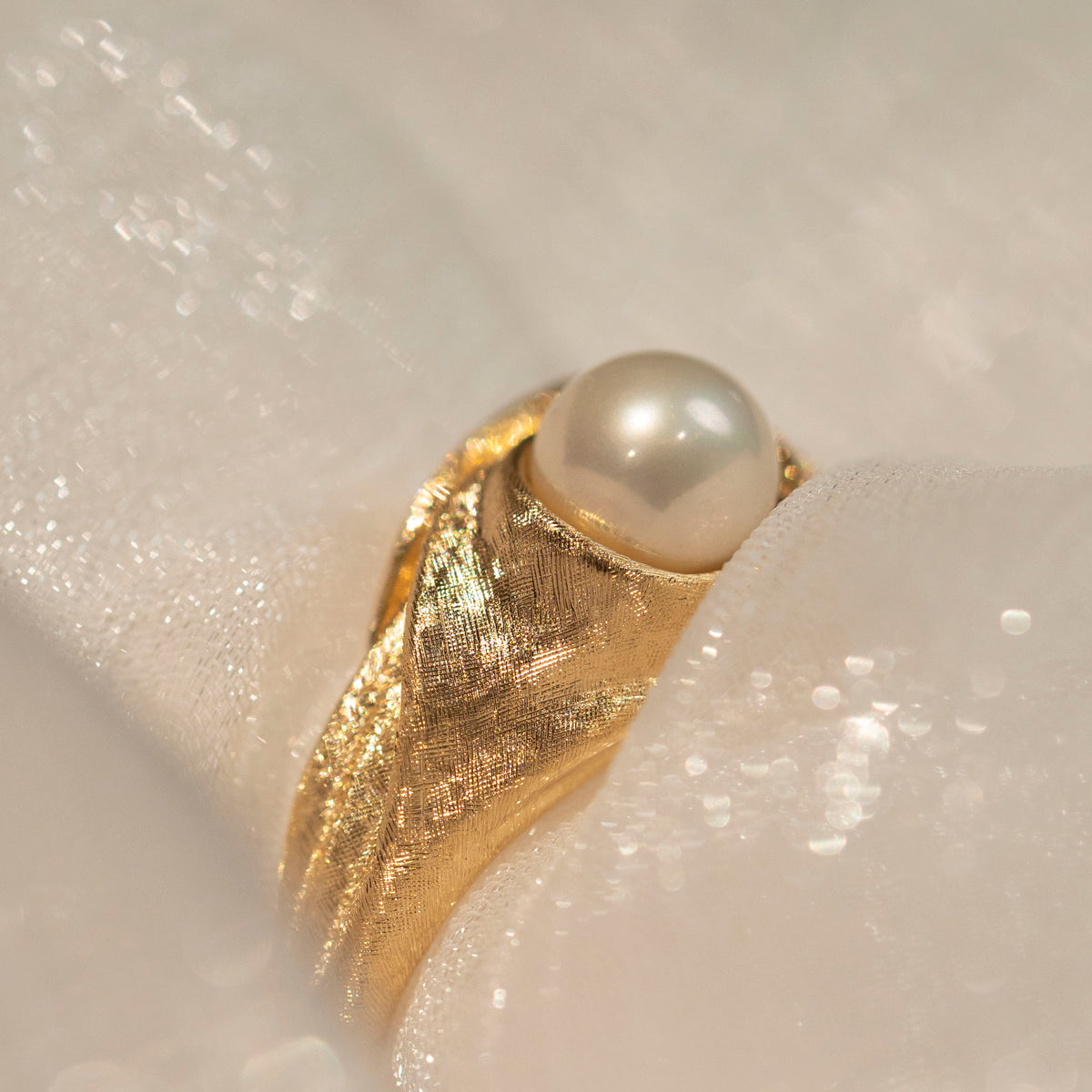 Detail of the freshwater pearl and fine hand-worked gold lines, with sheer fabric around the ring.