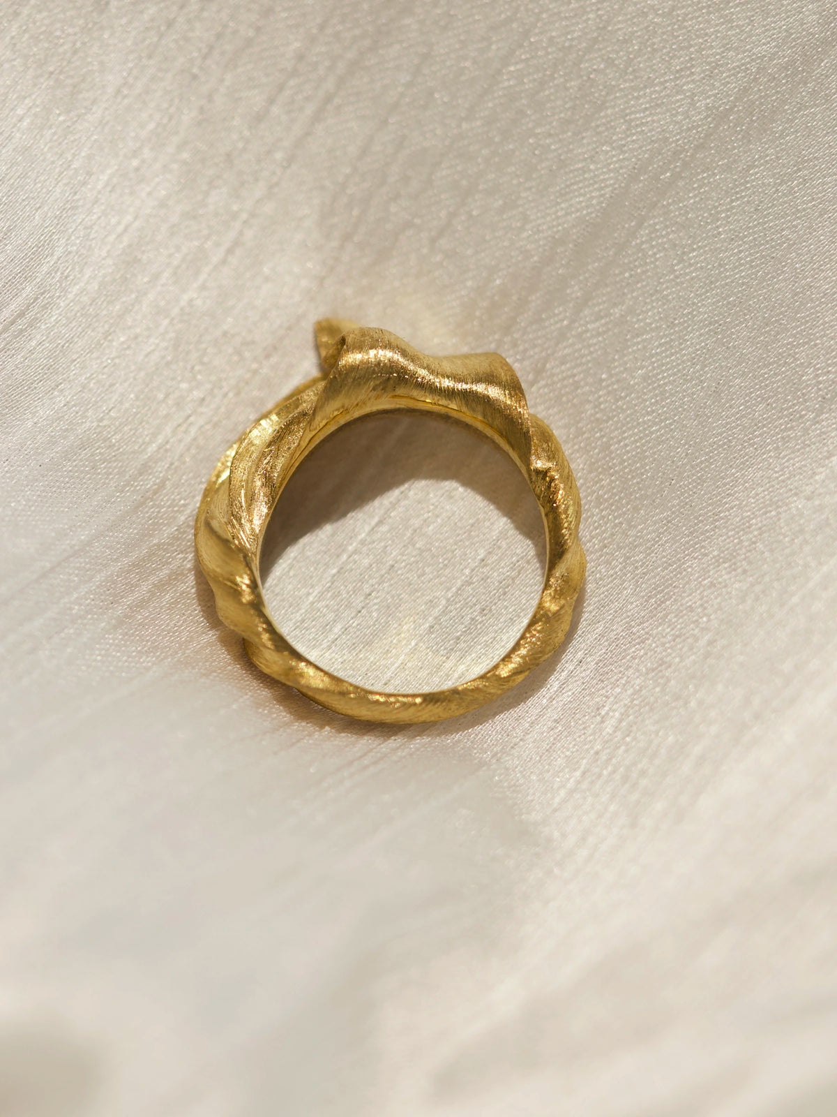 Back and inner view of the Silk in Gold ring on pale fabric, showing the continuous band and sculptural edges.