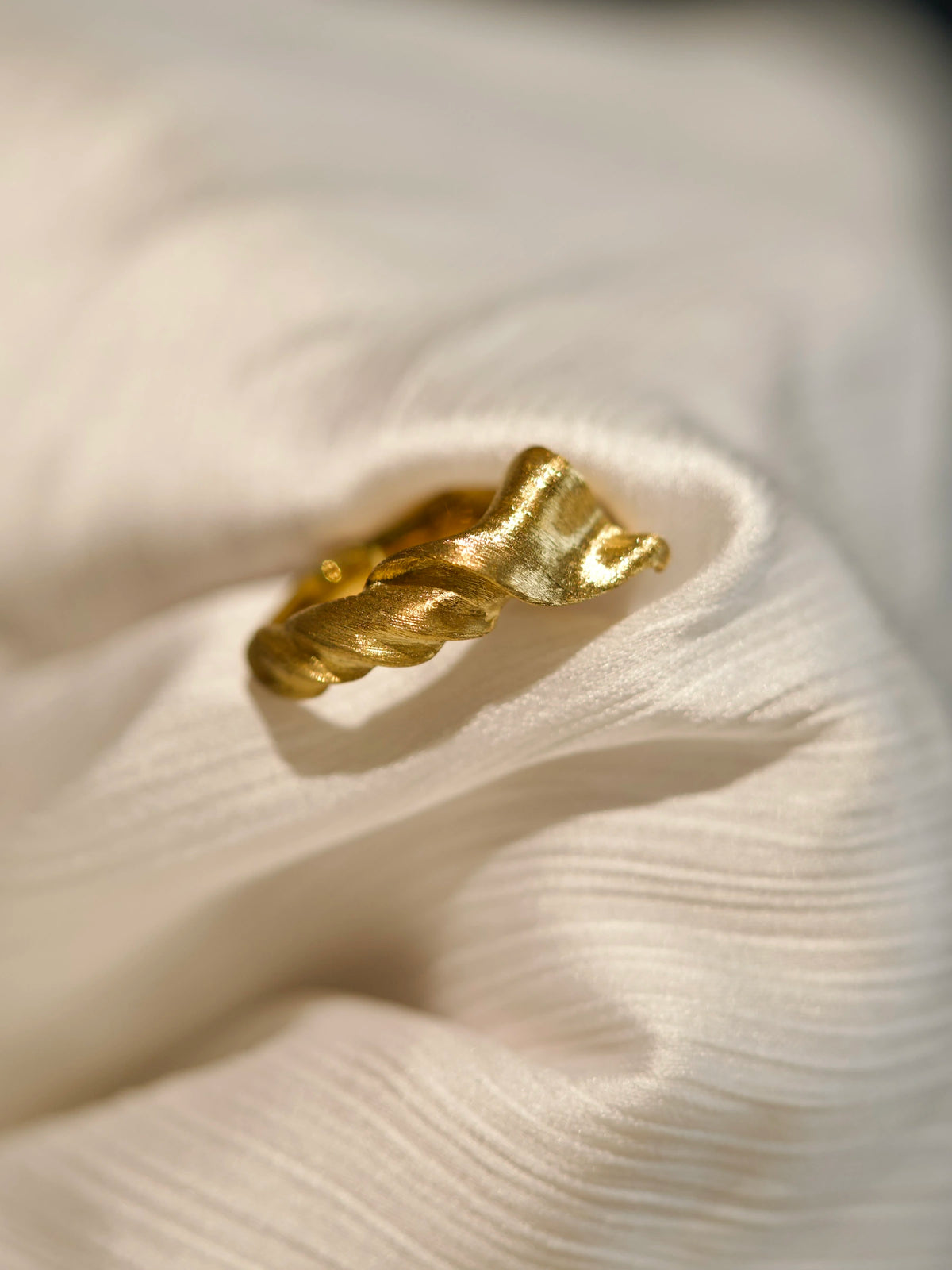 Side detail of the Silk in Gold ring, showing fine hand-worked lines along the twisted folds.